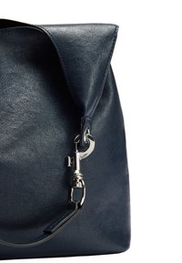 Granatowa skórzana torebka o wyraźnym kształcie, z dużą klapą zasuwaną i srebrnymi elementami do mocowania paska.