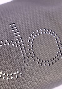 Tejido de malla gris que muestra un patrón perforado formando las letras "d" y "o". La textura es transpirable y texturizada, con un brillo sutil.