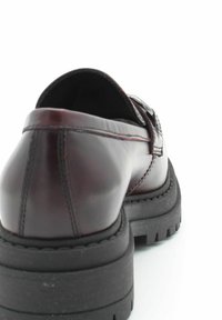 Dunkelburgunderfarbene Lederschuhe mit abgerundetem Zehenbereich, ausgestattet mit einer dicken schwarzen Gummisohle mit Profil und kontrastierenden Nahtdetails.