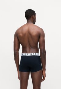 Boxeri negri, cu un logo alb "HILFIGER" pe banda elastică, având un design ajustat și o textură de material neted.