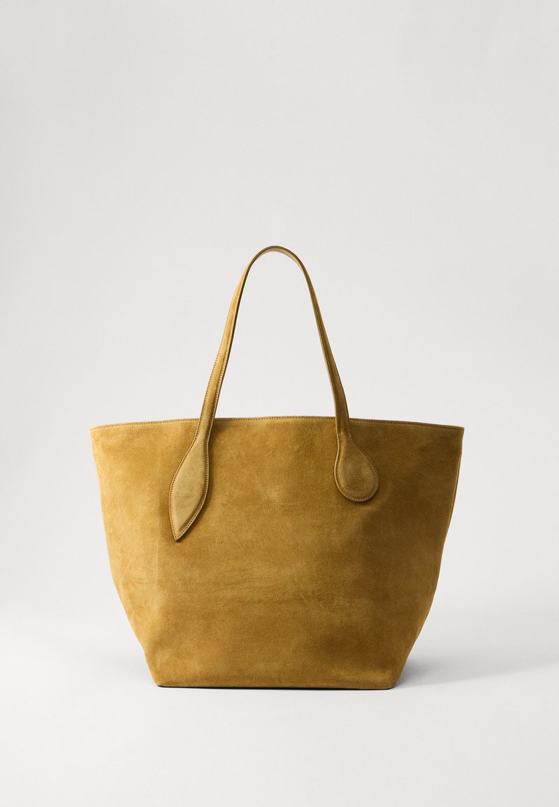 Sac fourre-tout en suède jaune avec deux longues poignées, texture lisse et design spacieux ; présente des accents arrondis sur les attaches des poignées.