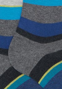 Calze grigie con strisce orizzontali in blu, nero, verde acqua e giallo che coprono la zona del piede e della caviglia, mostrando una trama a maglia e un contrasto di colori.