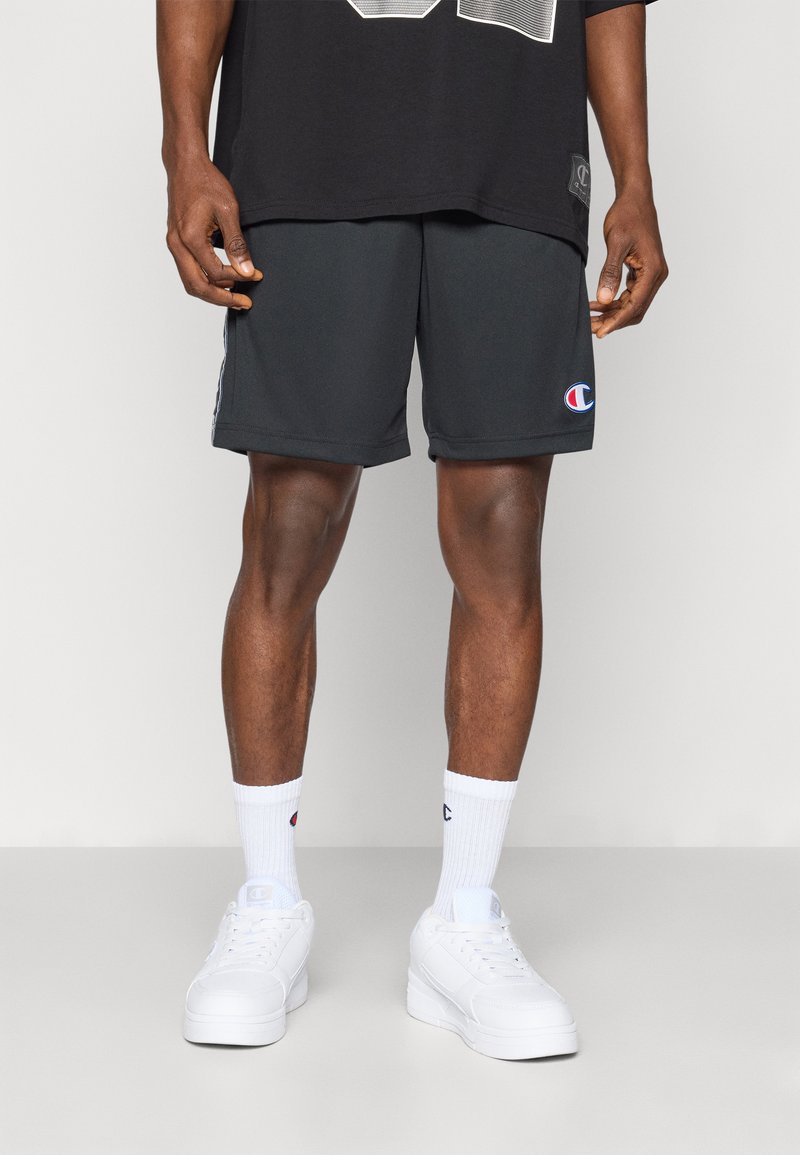 Grå idrettsshorts laget av myk stoff, med et sideskilt, kombinert med hvite crew-sokker og hvite sneakers. Enkle linjer og passform.