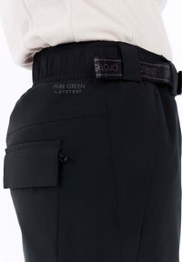 Zwarte broek van lichtgewicht stof, met een elastische tailleband, een zijzak met flap en een logo-label op de achterkant.