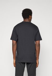 Sort bomulds t-shirt med korte ærmer, rund halsudskæring og enkelt design. Har et lille logoaccent på venstre ærme.