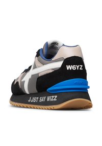 Sneaker con tomaia in suede e tessuto nero, grigio e beige, logo bianco, accentuazione blu sul tallone e suola in gomma con testo stampato.