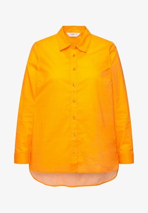 Camisa de manga larga color naranja hecha de algodón, con cierre frontal de botones, cuello clásico y dobladillo redondeado con la parte trasera ligeramente más larga.