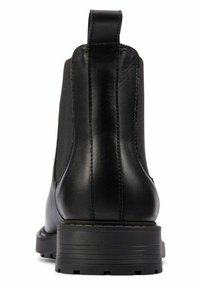 Bota Chelsea de cuero negro con paneles elásticos a los lados, tira en la parte trasera y suela de goma gruesa y con relieve, vista desde la parte trasera.