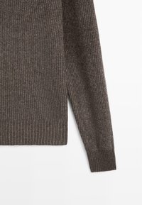 Pull en maille côtelée marron foncé avec des manches longues et des fentes sur les côtés. La texture du tissu est douce, avec un léger éclat et des variations de couleur subtiles.