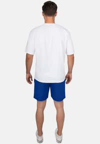 Witte katoenen T-shirt met korte mouwen, gecombineerd met blauwe shorts. De shorts hebben een gladde textuur en een afgeronde zoom.