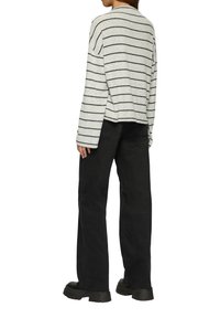 Grijze lange mouwen top met zwarte horizontale strepen, gecombineerd met zwarte wijde broek en chunky zwarte schoenen.