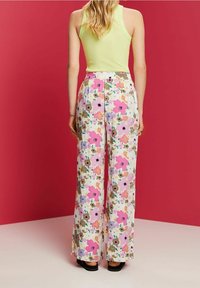Vloeiende wijde broek in pastel bloemenstof, met roze, paarse en beige tinten, voorzien van een elastische tailleband en een gladde textuur.