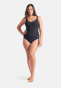Sort badedragt med rund halsudskæring, tykke stropper og glat, elastisk stof. Har et diskret logo på hoften.