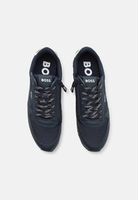 Sneakers blu navy con superficie in rete e sintetica, dotati di lacci neri e bianchi, e un logo "BOSS" sulla linguetta e sui pannelli laterali.