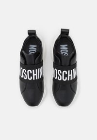 Baskets noires avec une tige en cuir lisse, équipées d'une large bande élastique noire avec le texte blanc « MOSCHINO » et des semelles en caoutchouc blanches contrastantes.