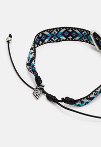 Pulseira tecidos com uma base preta e padrões em turquesa e rosa. Corda ajustável com um charme em tom prateado e detalhes de nó.