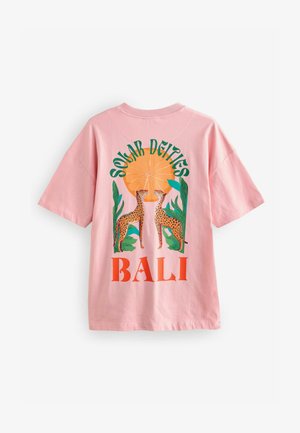 Roosa puuvillane T-särk, millel on graafiline disain kahe leopardi, troopiliste lehtede ja tekstiga "SOLAR DEITIES BALI" oranžis ja rohelises.