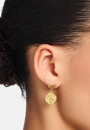 Goldohrringe mit einem kreisförmigen Anhänger, der kunstvoll verziert ist, einem kleinen roten Akzent darüber und einer glatten, polierten Oberfläche.