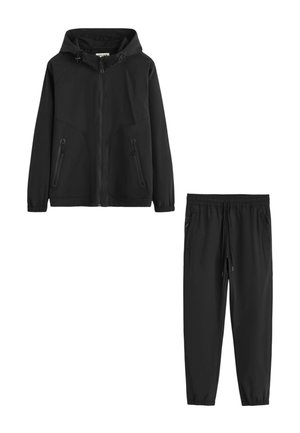 Veste noire à capuche avec fermeture éclair, poches latérales zippées et pantalon noir assorti avec cordon, poches zippées et poignets élastiques.