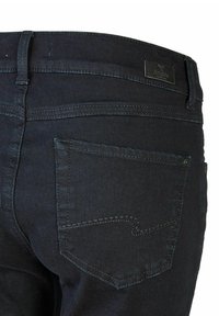 Donker denim jeans met een hoge taille, achterzakdetails en subtiele stiksels. Het materiaal heeft een gladde textuur.