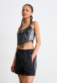 Top cropped preto com riscas brancas e calções pretos de cintura elástica com um logótipo discreto. Textura suave, design desportivo.