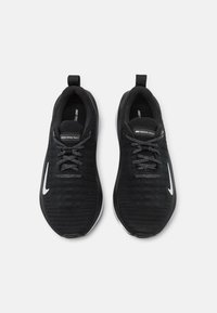 Baskets de sport noires avec un dessus en maille texturée, lacets gris et un swoosh Nike blanc. Dotées d'une languette et d'une semelle rembourrée.