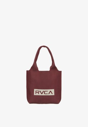 Tumepunane kandekott kitsaste valgete vertikaaltriipude ning laia sangaga, millel on ristkülikukujuline beež laik peal, millel on julgete tähtedega kiri "RVCA".