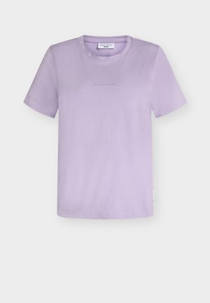 Camiseta de manga corta color lila con cuello redondo, logo sutil en el frente y una pequeña etiqueta blanca lateral sobre fondo blanco liso.