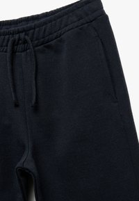 Mørkeblå sweatpants lavet af blødt materiale, med elastisk talje og snørrelukning samt sidelommer. Glat tekstur, afslappet design.