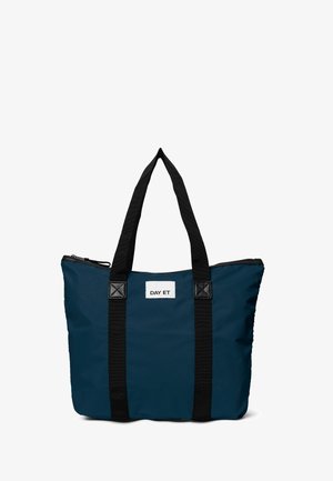 Mørkeblå tote bag med sorte stropper, der har en hvid label med teksten "DAY ET," designet til afslappet brug eller rejser.