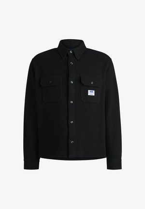 Schwarzes Hemd mit Knopfleiste aus strukturiertem Stoff, das über zwei Brusttaschen und ein kleines Markenlabel auf der linken Tasche verfügt.