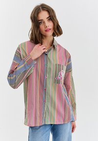Koszula z długim rękawem w paski, z wielokolorowymi pionowymi paskami w odcieniach różu, zieleni, niebieskiego i żółtego, z naszywaną kieszenią i wyszywanymi detalami.