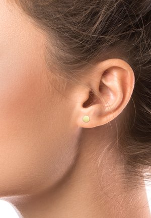 Goldfarbene kleine Ohrstecker mit einem glatten, runden Design, das vor einem neutralen Hautton präsentiert wird, mit einfacher Gestaltung und minimalistischem Reiz.