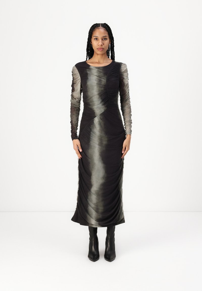 Rochie neagră cu mânecă lungă, cu textură pliată, având un design gradient de la întunecat la deschis. Asortată cu cizme negre cu toc înalt.