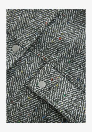 Siv herringbone tkanina z barvitimi pikami, ki ima srebrne pritisne gumbke. Teksturna mešanica volne z diagonalnim vzorcem.