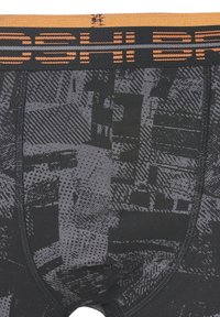 Boxer shorts negros con un diseño texturizado y patrones variados en tonos grises. La cinturilla es naranja con letras negras.