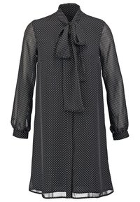 Robe noire à pois avec un col à nœud, manches bouffantes longues et texture transparente. Design à mi-longueur avec une coupe décontractée.
