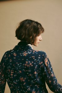 Długo rękawowa, ciemnoniebieska bluzka z kwiatowym wzorem w kolorze pomarańczowym, białym i niebieskim. Lekki, zwiewny materiał z kołnierzykiem.