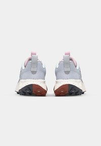 Baskets de sport grises claires avec des accents roses, empeigne en maille texturée, talon rembourré, et semelle extérieure mouchetée blanche et rouge.