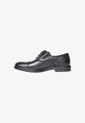 Scarpa da uomo in pelle nera con dettagli brogue, allacciatura frontale e tacco basso, mostrata di lato su uno sfondo bianco.