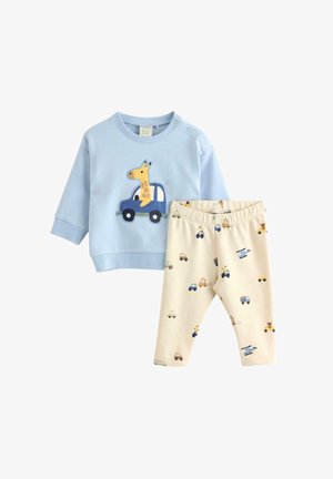 Sweatshirt bleu clair avec une applique de girafe dans une voiture. Pantalons crème avec des motifs de véhicules colorés. Tissu doux, manches longues, taille élastique.