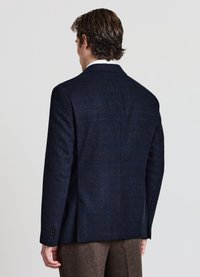 Blazer in tessuto navy con una vestibilità slim, rever a scollo a V e polsini con bottoni. Design su misura, con una fessura singola sul retro per facilitare i movimenti.