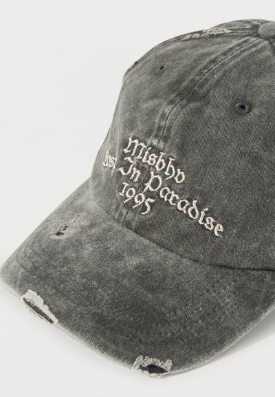 Φθαρμένο μαύρο καπέλο μπέιζμπολ με σκισίματα και άσπρο κεντητό κείμενο "Misbby The Jn Paradise 1995" στην μπροστινή πλευρά.