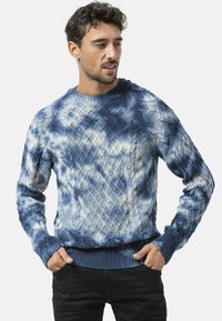 Blauwe gebreide trui met een gestructureerd diamantpatroon, voorzien van een ronde halslijn en geribde manchetten en zoom. Soepele stof in tinten lichtblauw en donkerblauw.