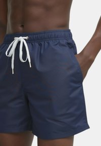 Pantaloni da bagno blu navy realizzati in materiale leggero, con vita elastica e cordino bianco, dotati di tasche laterali.