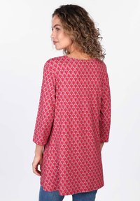 Rote Tunika mit Muster und dreiviertelÄrmeln, die ein Blattdesign in Rosa- und Cremetönen zeigt. Leichter Stoff mit lockerer Passform.