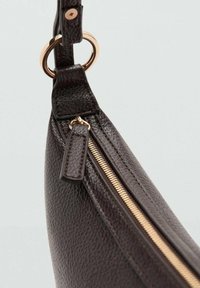 Bolso de mano de cuero marrón con un acabado texturizado, que presenta un cierre dorado y detalles de herrajes, diseñado con una forma curva y una correa lateral.