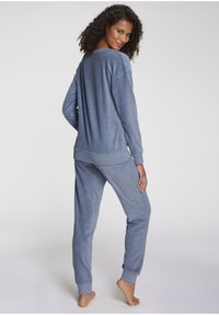 Gray, soft, fleece loungewear set featuring a long-sleeve top with a relaxed fit and matching jogger pants with elastic cuffs.