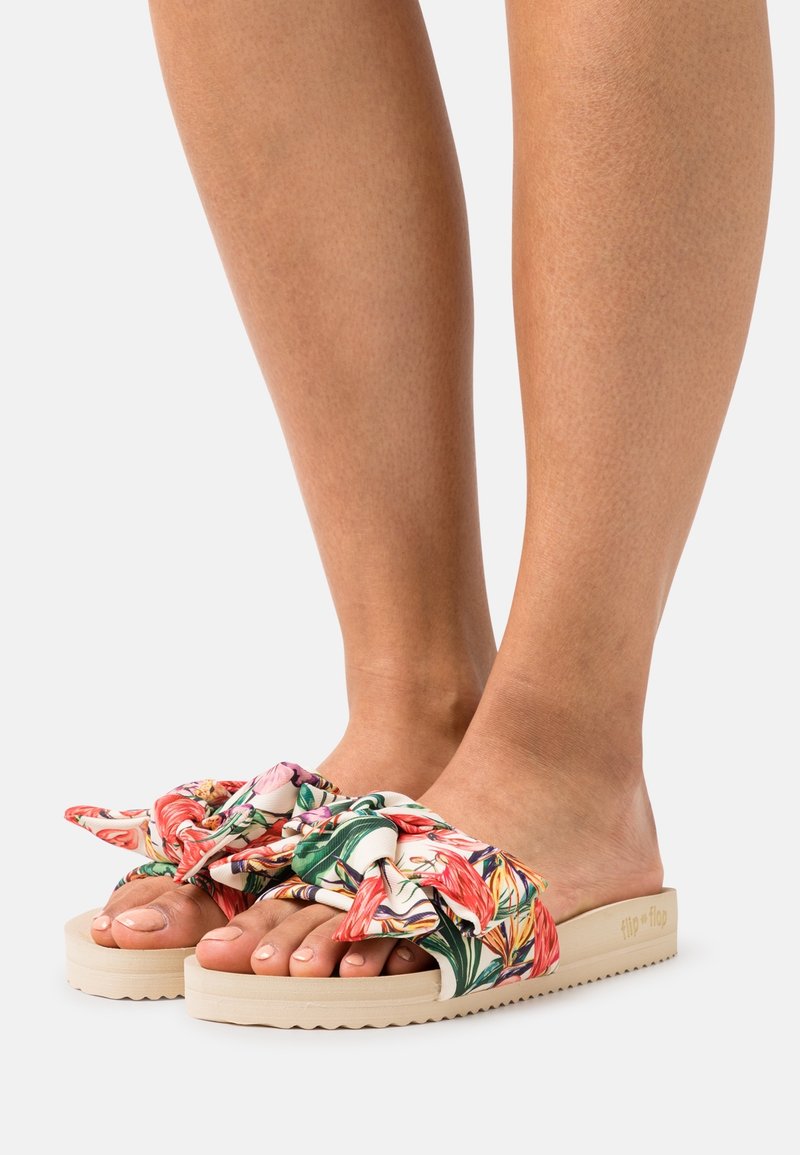 Květnové skluzné sandály s růžovým a zeleným vzorem. Měkký textilní svršek, robustní smetanová podrážka a detail se svázanou mašlí.