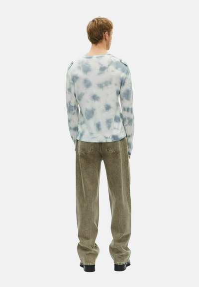 Maglietta a maniche lunghe con stampa tie-dye in blu chiaro e bianco, con dettagli sulle spalle. Abbinata a pantaloni larghi verdi oliva.